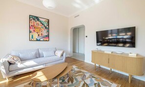 A modern living room with a sofa, a coffee table, a TV, and a wooden cabinet. - DISCOVER THE CHARM OF THE FRENCH RIVIERA IN THE HEART OF CANNES. (Cannes)