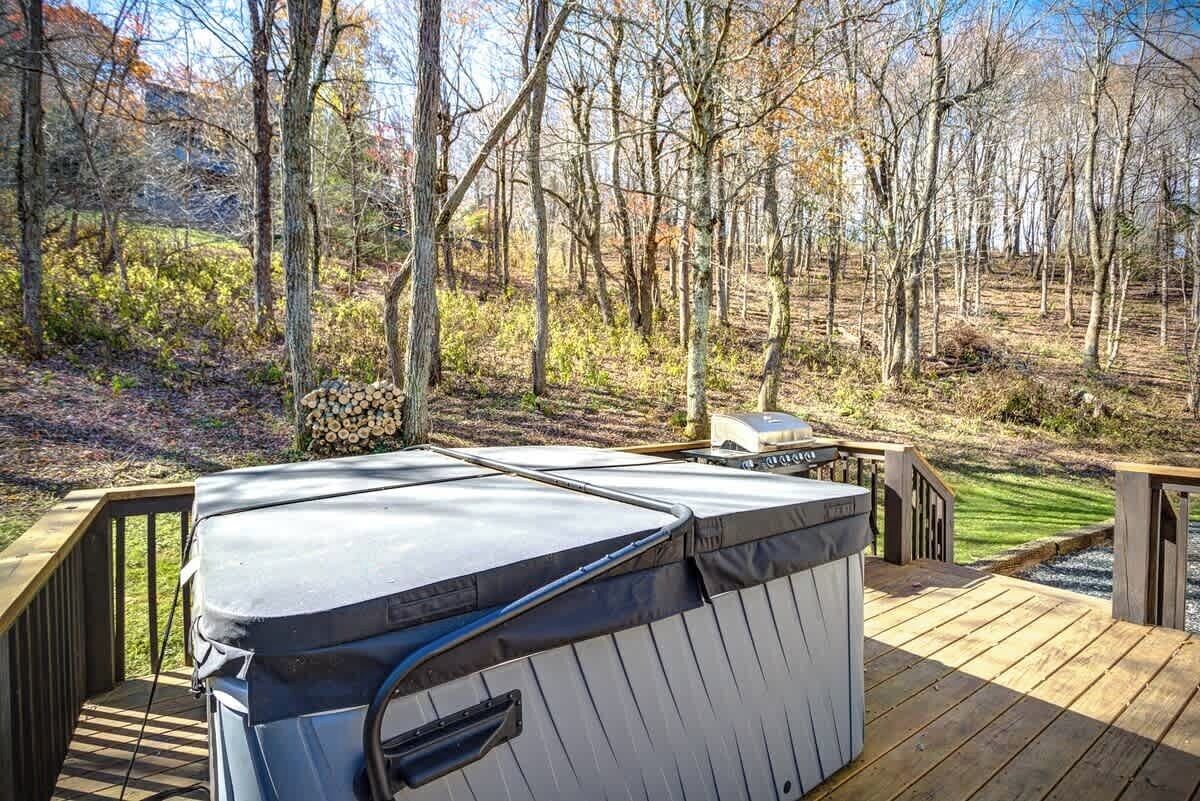 Ein Whirlpool auf einer Holzterrasse mit Blick auf eine bewaldete Landschaft.