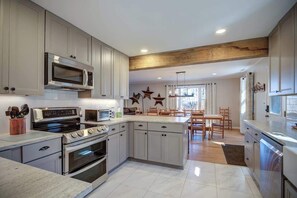 A modern kitchen with a central island, built-in appliances, and a dining area with natural light. - Snowflake Lodge - 4BR on App Ski Mountain! (Blowing Rock)