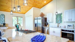 A modern kitchen with a large island, stainless steel appliances, and a wooden ceiling. - Blue Mountain Breeze with multi-mountain range vie (Blowing Rock)