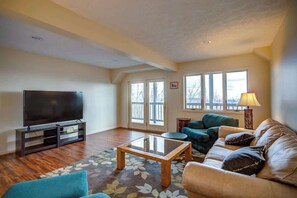 A living room with a flat-screen TV, a sofa, a coffee table, and a patterned rug. - Blue Mountain Breeze with multi-mountain range vie (Blowing Rock)