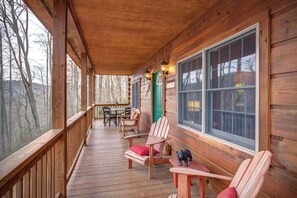 Une terrasse en bois, avec des chaises et une table, donnant sur une zone boisée.