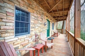 Une terrasse en bois avec des murs en pierre et une véranda couverte.