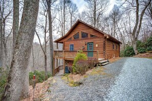 Une cabane en bois dotée d’un balcon, entourée d’arbres.