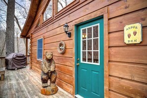 A wooden cabin with a green door, a bear statue, and a sign that reads 'ARBOR DEN'. - Arbor Den Log Cabin 3 Bedroom, 3 Bath, Pet friendly (Blowing Rock)