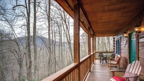 A wooden deck with a view of a forest and mountains. - Arbor Den Log Cabin 3 Bedroom, 3 Bath, Pet friendly (Blowing Rock)