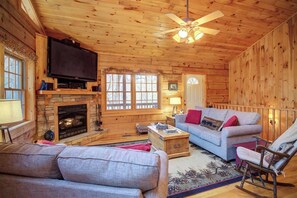 A log cabin interior with a fireplace, television, and seating area. - Arbor Den Log Cabin 3 Bedroom, 3 Bath, Pet friendly (Blowing Rock)
