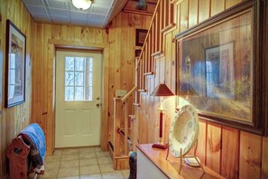 A wooden interior with a door, a staircase, and a framed painting. - Arbor Den Log Cabin 3 Bedroom, 3 Bath, Pet friendly (Blowing Rock)