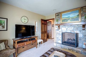 A living room with a fireplace, television, and a stone wall. - Blissful Vista has breathtaking gorge views, seclu (Blowing Rock)