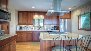 A modern kitchen with wooden cabinets, a stainless steel range hood, and a central island with bar stools. - Blissful Vista has breathtaking gorge views, seclu (Blowing Rock)