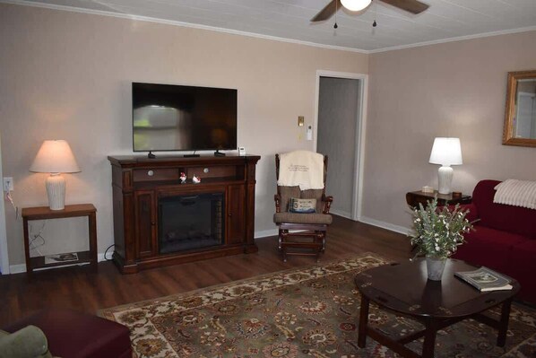A living room with a fireplace, a television, a red sofa, and a patterned rug. - Minute to Main - Steps to Main St Blowing Rock (Blowing Rock)
