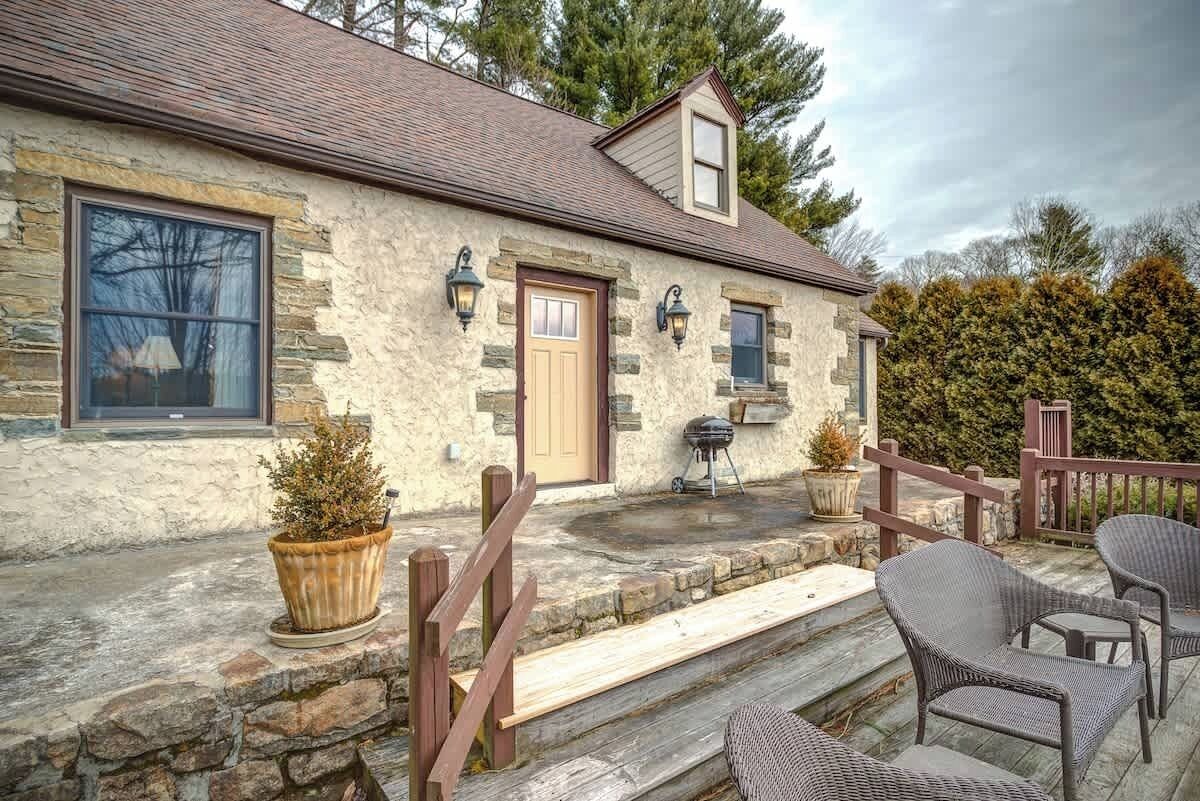 A stone house with a wooden porch, a door, and a window.