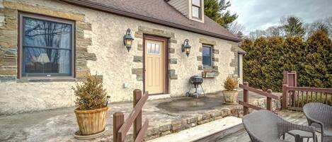 A stone house with a wooden porch, a door, and a window.