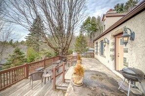 A wooden deck with outdoor furniture, a barbecue grill, and a stone wall with a door and windows. - The Hill is the best in country living, minutes fr (Blowing Rock)