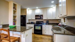 A kitchen with white cabinets, a black refrigerator, a microwave, a stove, and a green bowl on the counter. - The Hill is the best in country living, minutes fr (Blowing Rock)