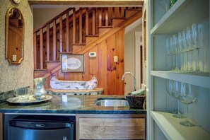 Una cucina con una scala in legno, un lavello e un portabicchieri per vino.