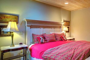 A bedroom with a wooden headboard, a red patterned bedspread, and a nightstand with a lamp. - The Hill is the best in country living, minutes fr (Blowing Rock)