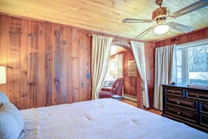 A wooden room with a bed, a chair, a dresser, and a ceiling fan.