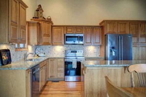 A kitchen with wooden cabinets, stainless steel appliances, and a granite countertop. - Fair Haven - Great App Ski Mtn Location! (Blowing Rock)