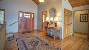 A spacious room with wooden flooring, a large rug, a console table with lamps, and a mirror above it. - Fair Haven - Great App Ski Mtn Location! (Blowing Rock)