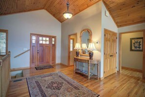 A spacious room with wooden flooring, a large rug, a console table with lamps, and a mirror above it. - Fair Haven - Great App Ski Mtn Location! (Blowing Rock)