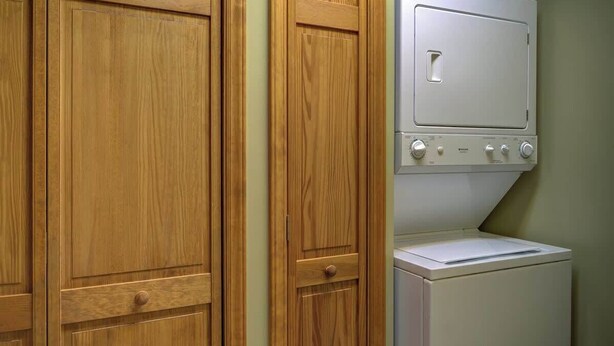A laundry room with wooden cabinets and a white washing machine. - Fair Haven - Great App Ski Mtn Location! (Blowing Rock)