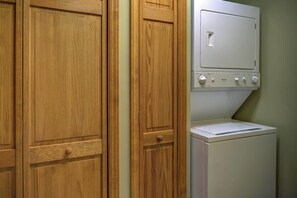 Una lavanderia con mobili in legno e una lavatrice bianca.