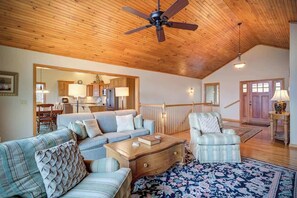 A spacious living room with a high ceiling, a wooden ceiling fan, a large sofa, a striped armchair, a coffee table, and a patterned rug. - Fair Haven - Great App Ski Mtn Location! (Blowing Rock)