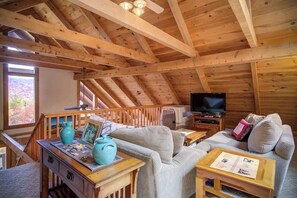 Ein Holzinterieur mit Fernseher, Sofa und einem Tisch mit Vase und Bilderrahmen.