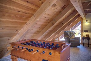 Ein Zimmer mit Holzboden, einem Kicker, einer Couch und einer Lampe.