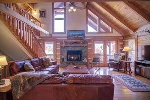 A spacious living room with a fireplace, leather sofa, and a staircase leading to an upper level. - Ollie's Overlook  fabulous multi-level cabin locat (Lenoir)