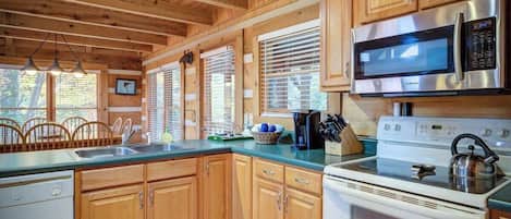 A kitchen with wooden cabinets, a stainless steel microwave, a white stove, and a sink.