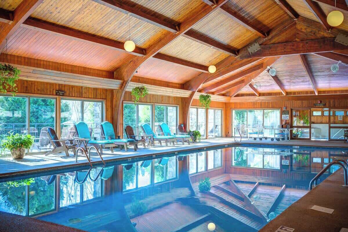 A large indoor swimming pool with lounge chairs and a wooden ceiling.