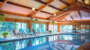 A large indoor swimming pool with lounge chairs and a wooden ceiling. - One Level Entry 3 bed 3 bath condo at Chetola (Blowing Rock)