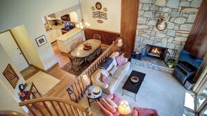 A spacious living area with a fireplace, a dining table, and a staircase leading to another level. - One Level Entry 3 bed 3 bath condo at Chetola (Blowing Rock)