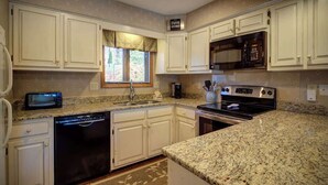 A kitchen with white cabinets, a microwave, an oven, a dishwasher, and a window with blinds. - One Level Entry 3 bed 3 bath condo at Chetola (Blowing Rock)