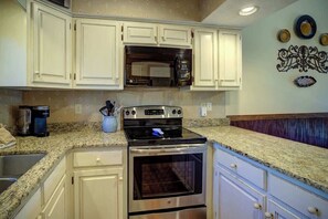 A kitchen with white cabinets, a stainless steel oven, a microwave, and a granite countertop. - One Level Entry 3 bed 3 bath condo at Chetola (Blowing Rock)