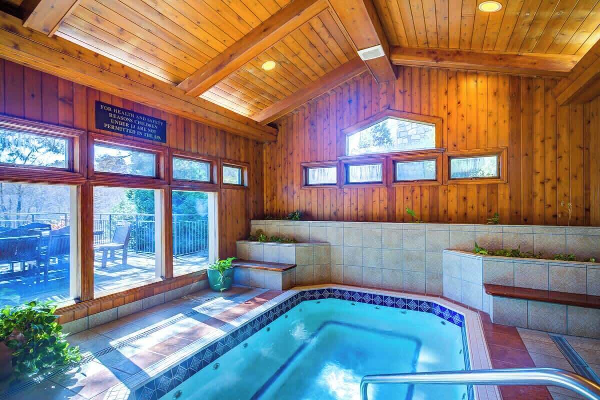 A spa area with a hot tub, wooden walls, and large windows.