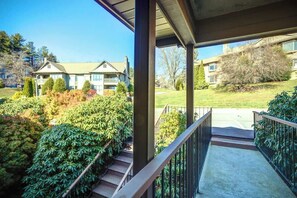 A covered outdoor area with a concrete pathway leading to a building entrance, surrounded by well-maintained greenery and residential buildings in the background. - One Level Entry 3 bed 3 bath condo at Chetola (Blowing Rock)