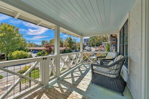 A covered porch with a view of a street and houses. - Little House on Main in Downtown Blowing Rock (Blowing Rock)