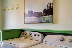 Ein Waschbereich mit zwei Whirlpool Waschmaschinen, einer grünen Arbeitsplatte und einem Bild an der Wand.