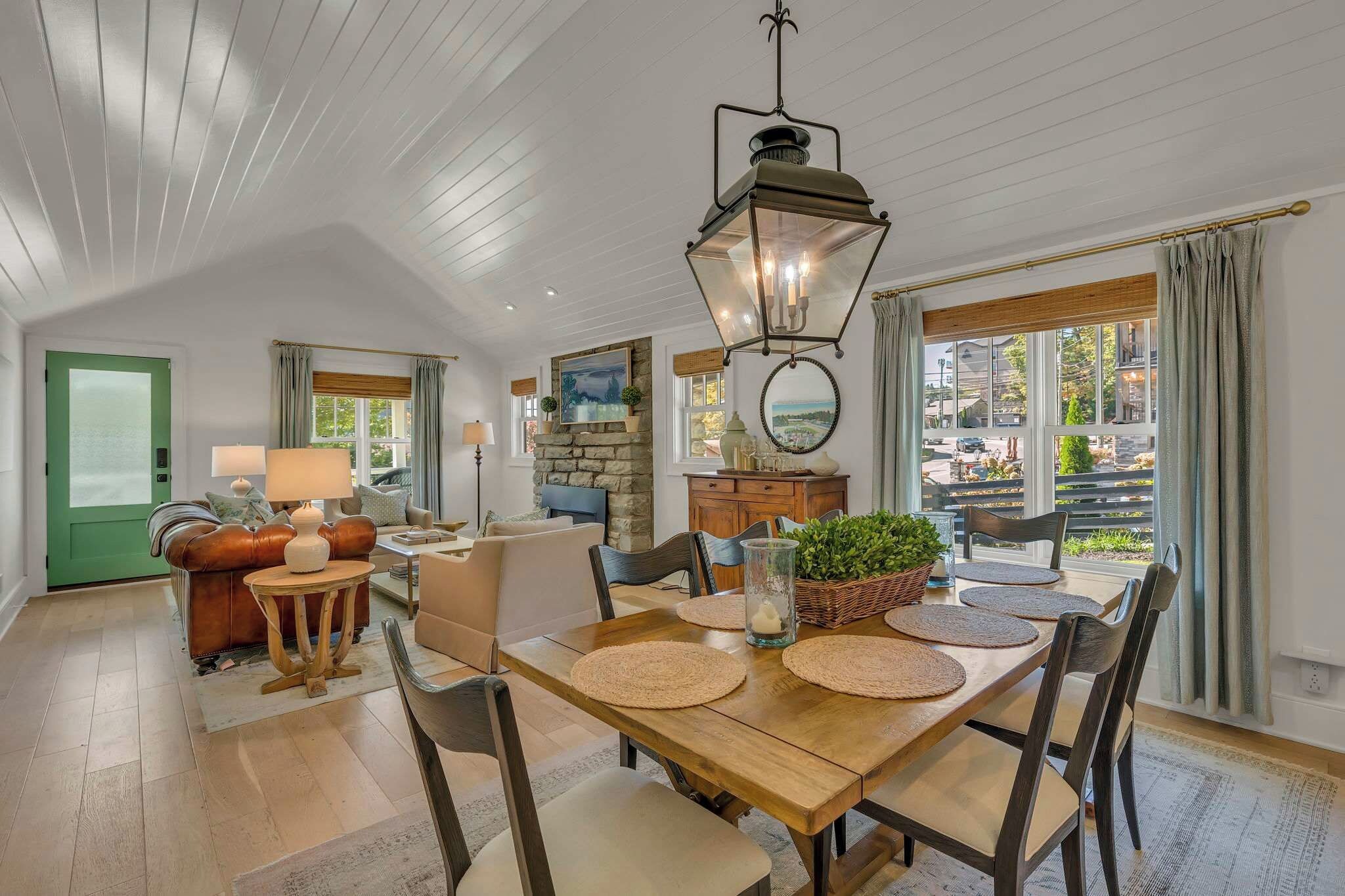 A spacious living room with a wooden dining table, comfortable seating, and a view of the outdoors.