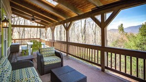 A covered outdoor deck with wicker furniture, a ceiling fan, and a view of trees and mountains. - 3 Bedroom 3 Bath Log Cabin just outside of Blowing (Blowing Rock)