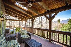 A covered outdoor deck with wicker furniture, a ceiling fan, and a view of trees and mountains. - 3 Bedroom 3 Bath Log Cabin just outside of Blowing (Blowing Rock)