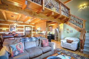 A spacious living area with a wooden ceiling, a sofa set, a white armchair, and a staircase with a decorative railing. - Cabin on Mistleoe 3 Bed 3 Bath Log cabin near Blowing Rock (Blowing Rock)