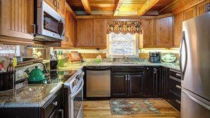 A kitchen with wooden cabinets, a microwave, a stove, a dishwasher, and a refrigerator. - 3 Bedroom 3 Bath Log Cabin just outside of Blowing (Blowing Rock)