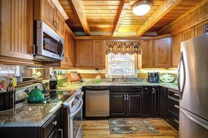 A kitchen with wooden cabinets, a microwave, a stove, a dishwasher, and a refrigerator. - 3 Bedroom 3 Bath Log Cabin just outside of Blowing (Blowing Rock)