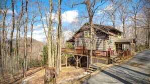 A cabin with a wooden deck, surrounded by trees and a clear sky. - 3 Bedroom 3 Bath Log Cabin just outside of Blowing (Blowing Rock)