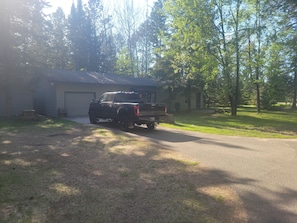 A black pickup truck parked in front of a garage with a lawn and trees in the background.