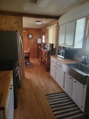 A kitchen with wooden cabinets, a refrigerator, a microwave, and a sink.